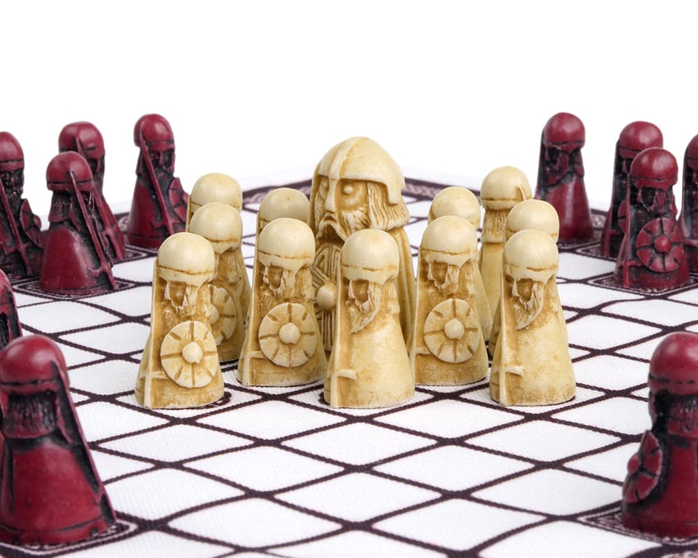 Historical Viking chess set with intricately carved pieces in battle formation on a checkered board.