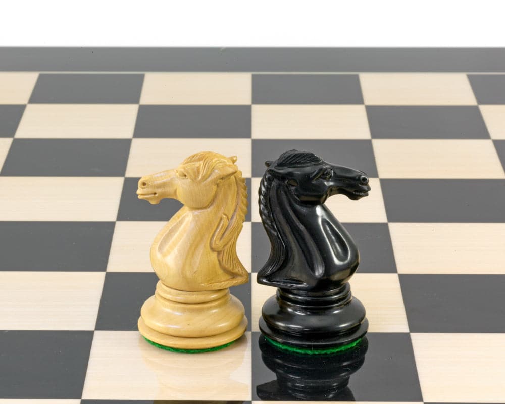 Ebony and boxwood knights from the Parthenon Series chess set on a chessboard, showcasing expert craftsmanship and luxury.