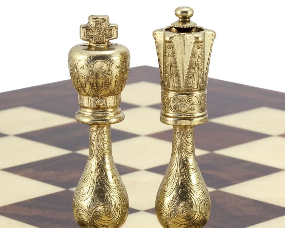 Brass king and queen chess pieces on a walnut and maple chessboard