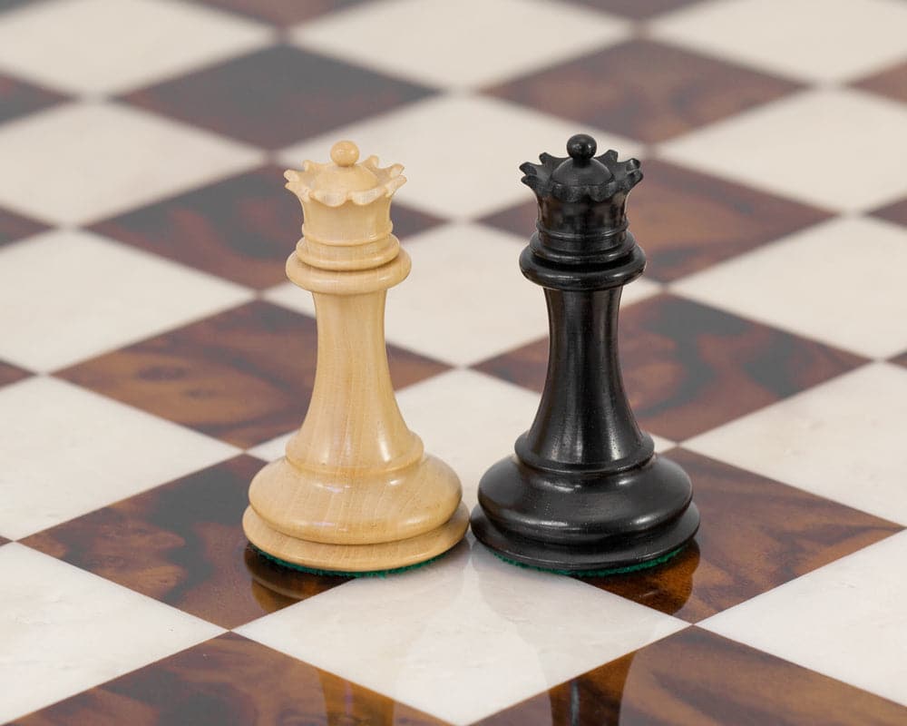 Black and white queen pieces from Black Sovereign Luxury Chess Set on Italian chess board with traditional Staunton design.