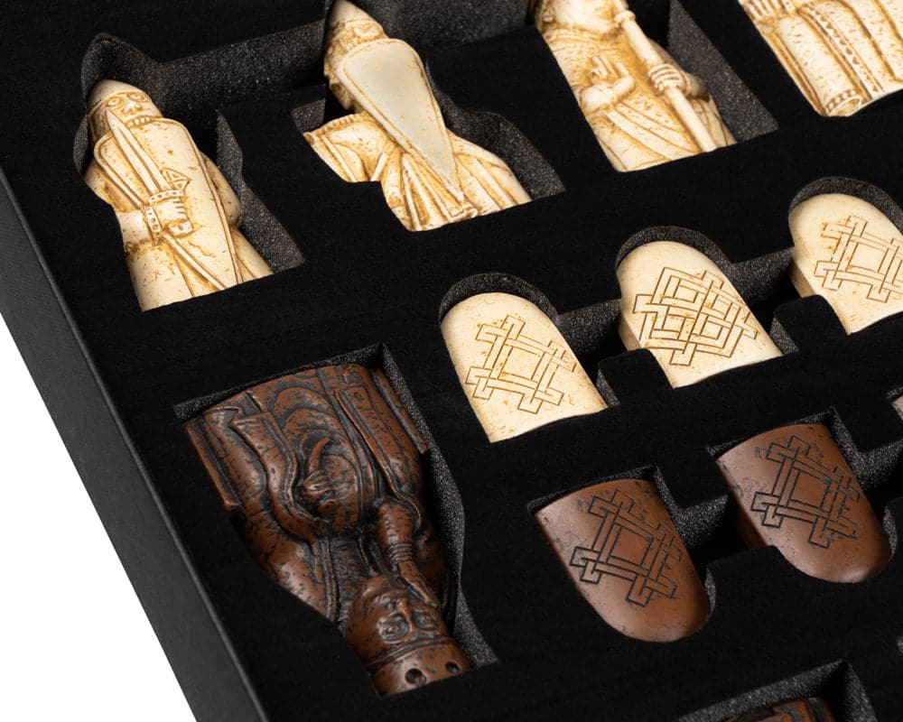 Close-up of Isle of Lewis chessmen in a storage box, featuring intricately detailed tiger ebony and maple chess pieces.