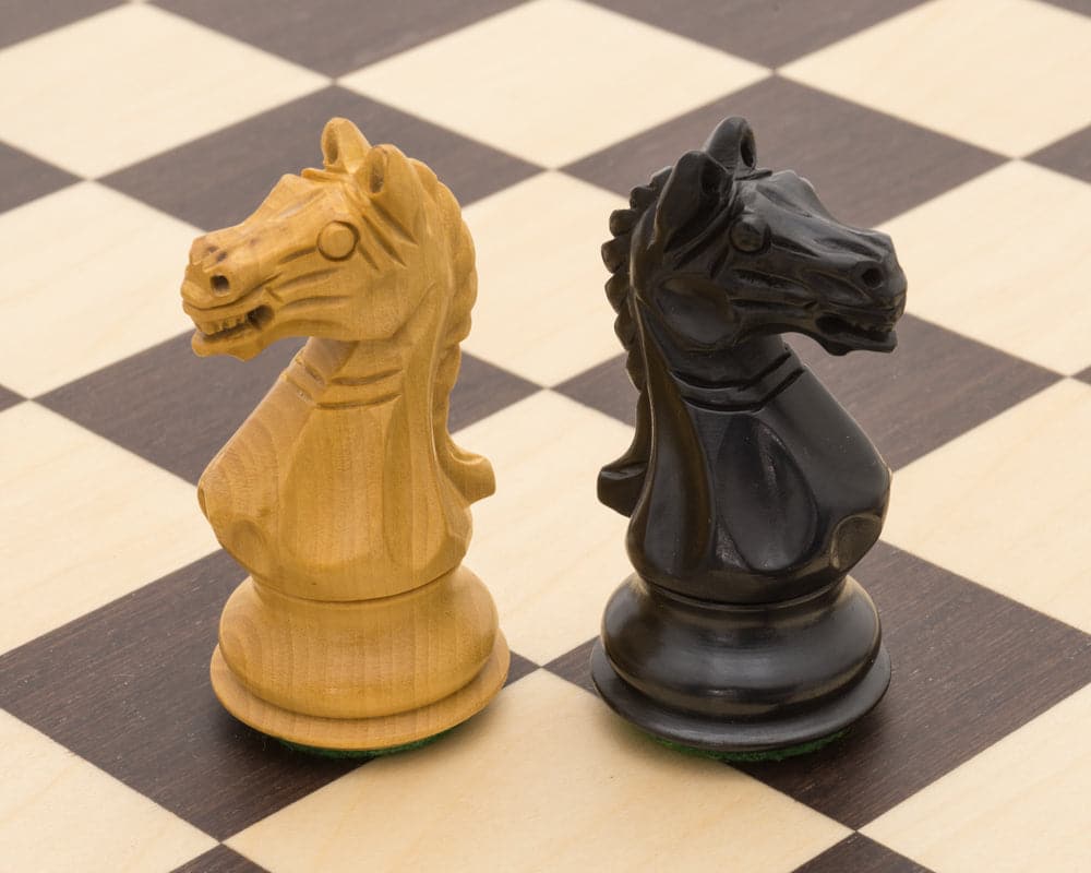 Handcrafted black and natural boxwood knight chess pieces on a 15.75 inch deluxe chess board, featuring classic Staunton design.